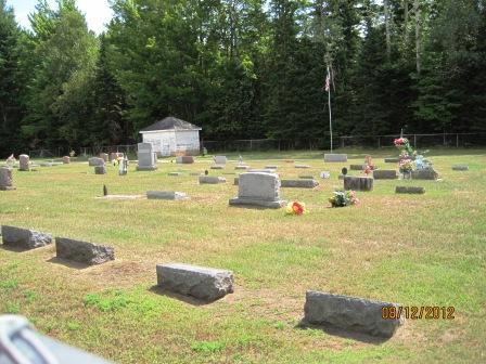 Sunlit cemetery with headstones and American flag.